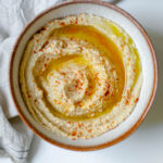 creamy homemade hummus garnished with olive oil and paprika