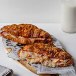 creamy croissants filled with ham and cheese topped with bechamel sauce served with coffee