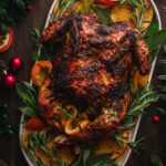 platter with roasted chicken in oranges and fennel, garnished with herbs and nuts